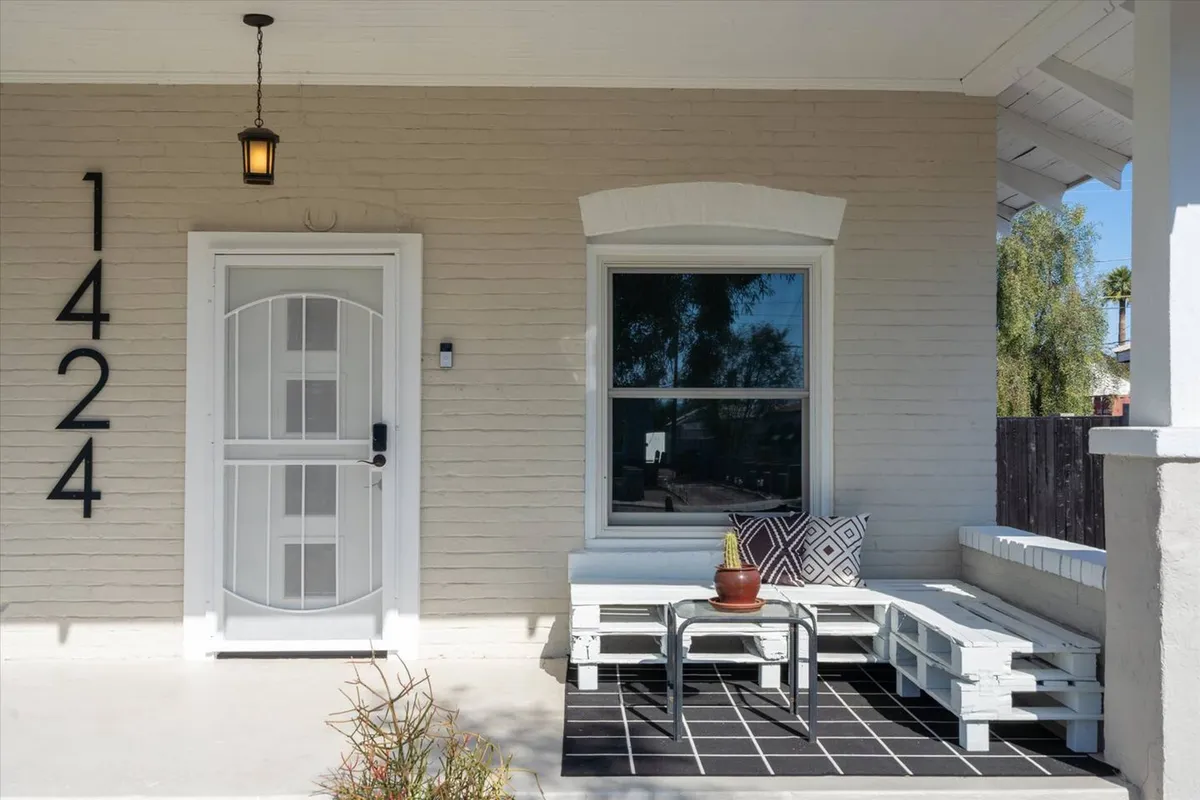 This exterior shot focuses on the home's front door, visible house number, a small seating area, and a potted plant. The setup is inviting, suggesting a welcoming entry and a place to relax outdoors or engage with neighbors.